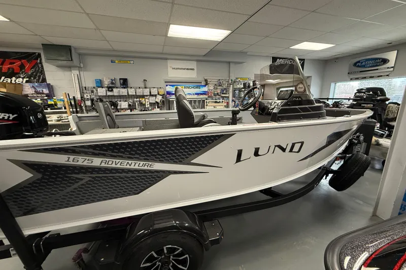 Slide: The Image of 2025 Lund 1675 Adventure SS boat displayed in a showroom with accessories. - 11