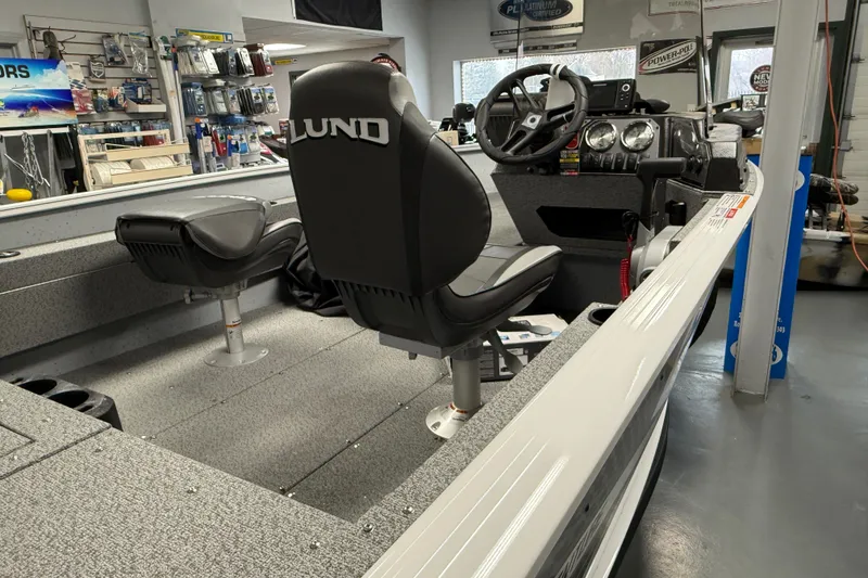 Slide: The Image of 2025 Lund 1675 Adventure SS boat interior with steering wheel and seating in showroom. - 2