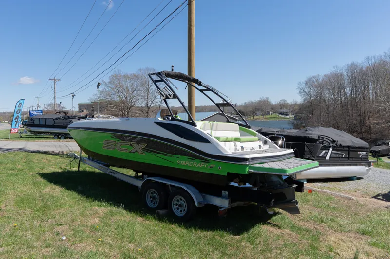 Slide: The Image of 2017 Starcraft Crossover 231 SCX IO SURF boat on trailer, green and white design. - 2