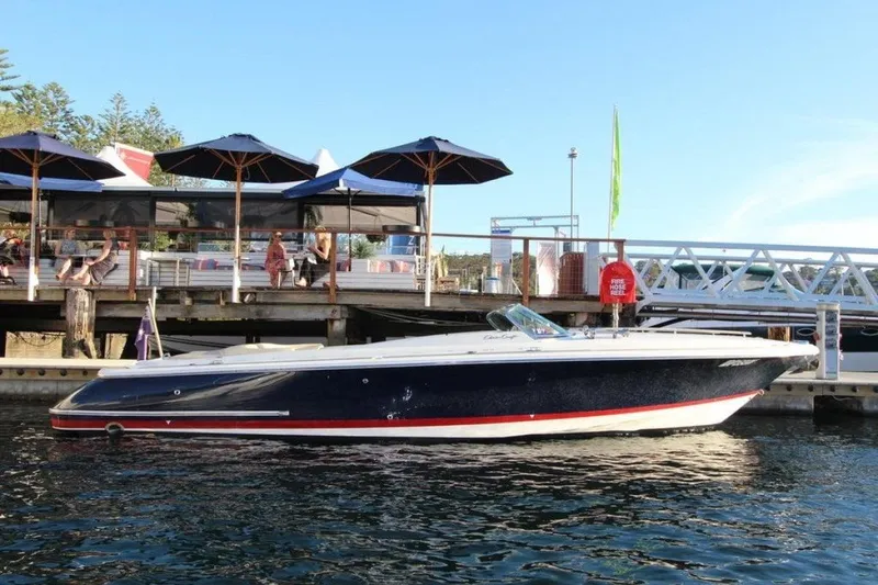 The Image of 2008 Chris-Craft Launch 28 boat docked near waterfront restaurant with umbrellas. - 0