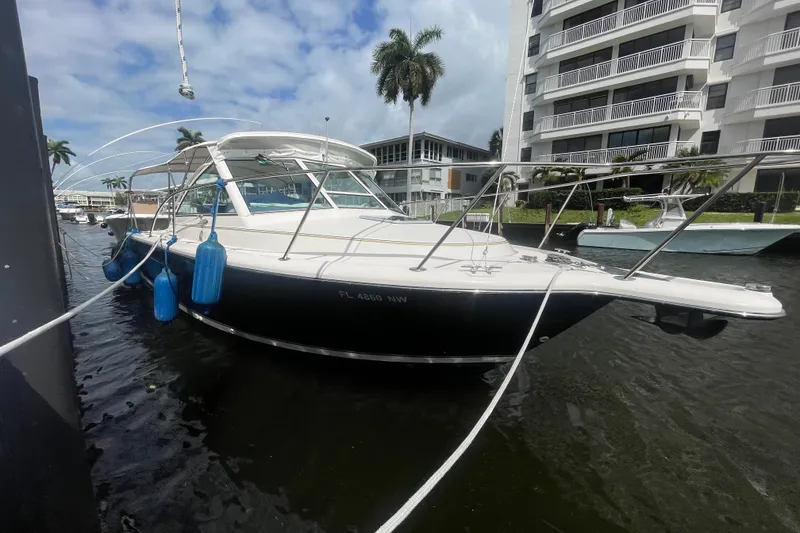 Slide: The Image of 2001 Tiara Yachts 2900 Coronet docked near waterfront buildings, with blue fenders. - 2