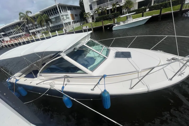 Slide: The Image of 2001 Tiara Yachts 2900 Coronet docked by waterfront homes, featuring a sleek design. - 6