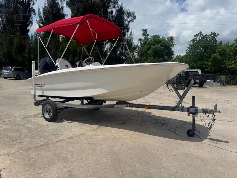 Slide: The Image of 2009 Boston Whaler 13 Sport boat with red canopy on trailer. - 0