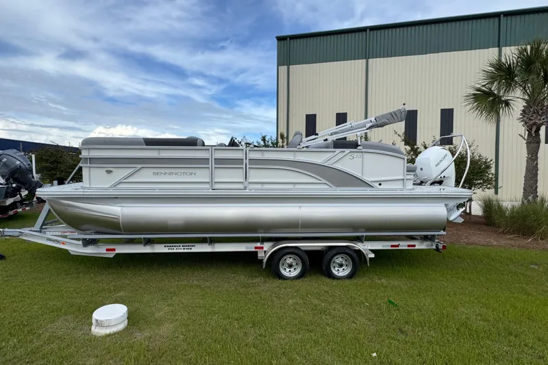 The Image of 2026 Bennington 22 SSB pontoon boat on trailer, parked on grass by a building. - 1