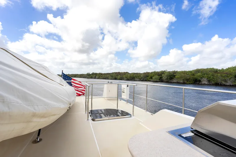 Slide: The Image of Luxury Fleming 85 yacht deck with American flag, river view, and clear blue sky, 2023 model. - 44