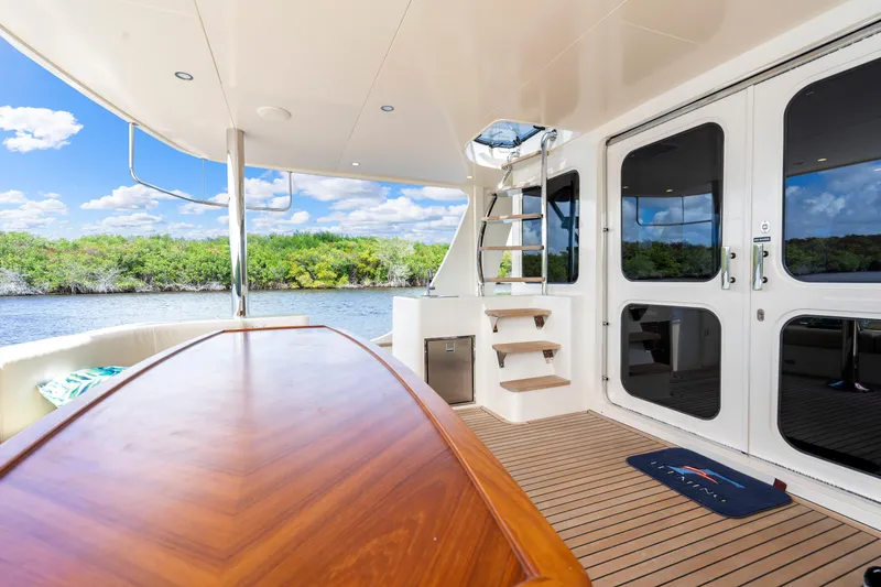 Slide: The Image of Luxurious Fleming 85 yacht deck with wooden table, scenic river view, 2023 model. - 51