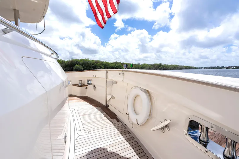 Slide: The Image of Luxurious 2023 Fleming 85 yacht deck with American flag, overlooking serene waters and lush greenery. - 53