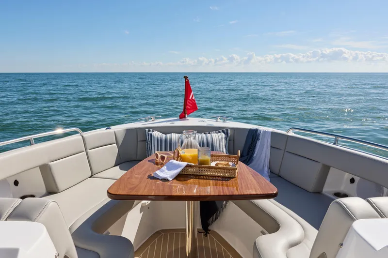 Slide: The Image of Luxury MJM 38x boat interior with table, ocean view, and sunny sky, 2026 model. - 10