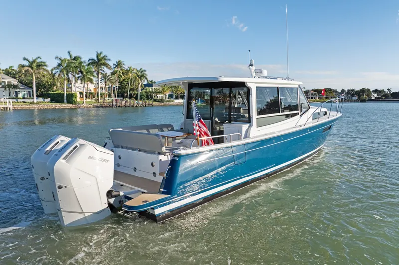 Slide: The Image of 2026 MJM 47 R boat cruising on a sunny day with palm trees in the background. - 1