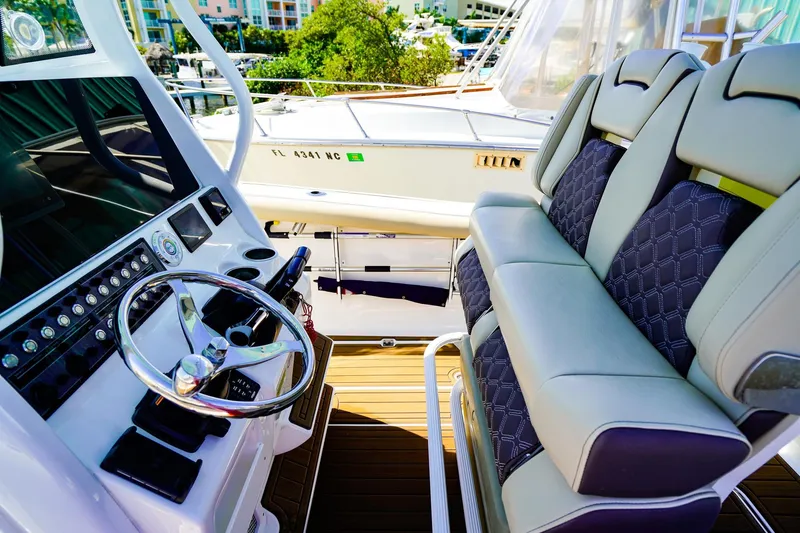 Slide: The Image of 2021 Tidewater 256 LXF boat interior with steering wheel and cushioned seating. - 11