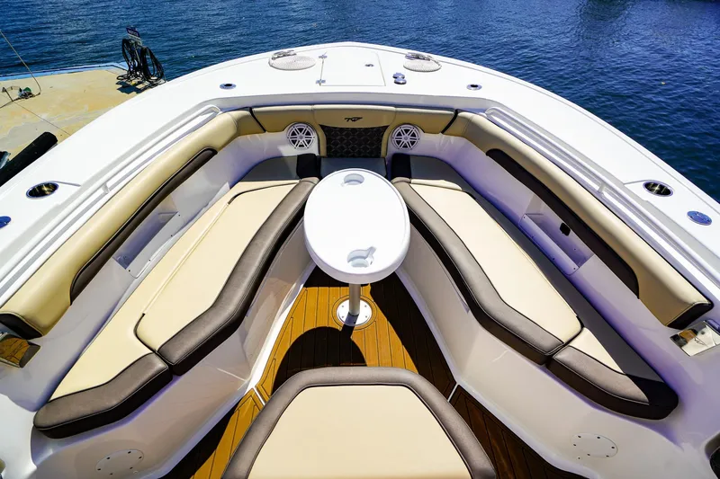 Slide: The Image of 2021 Tidewater 256 LXF boat interior with cushioned seating and table, docked by the water. - 22