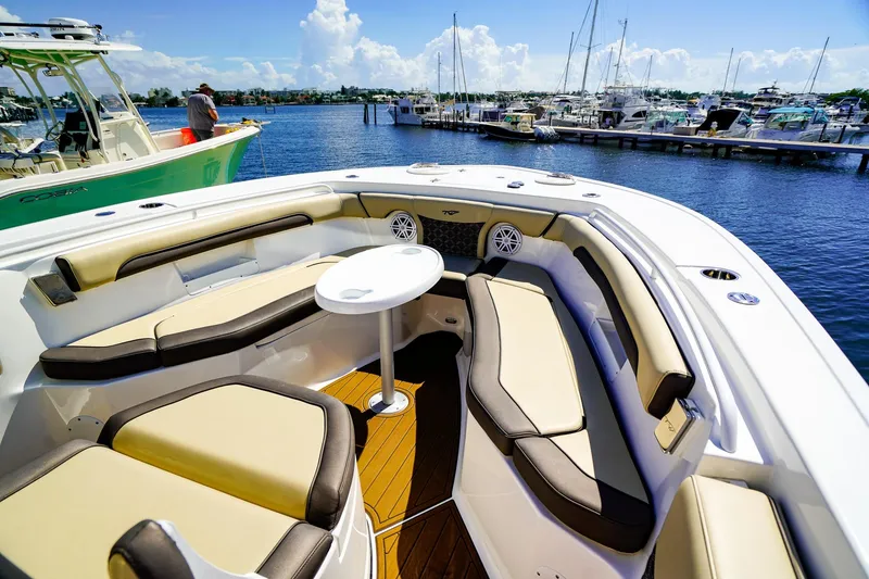 Slide: The Image of 2021 Tidewater 256 LXF boat interior with cushioned seating and table, docked at marina. - 25