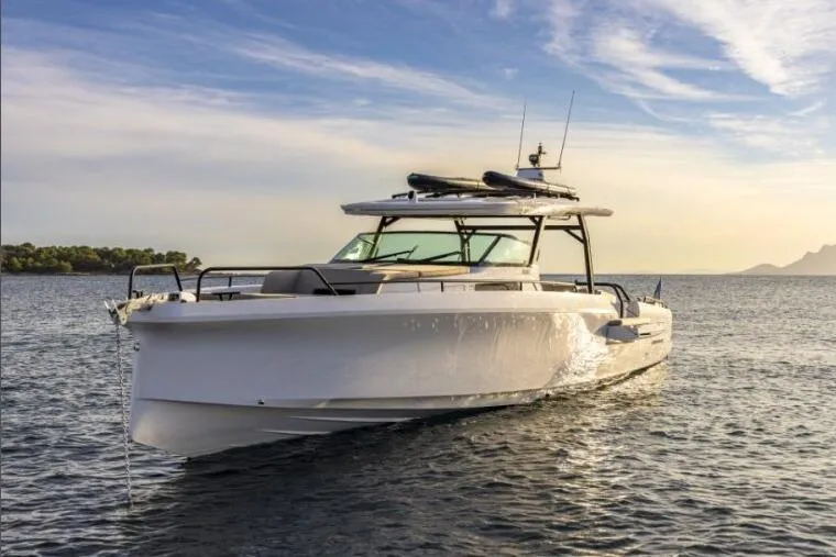 The Image of 2027 Axopar 45 Sun-Top boat cruising on calm water at sunset. - 0