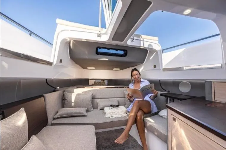Slide: The Image of Woman relaxing on 2027 Axopar 45 Sun-Top yacht interior, reading a magazine. - 11