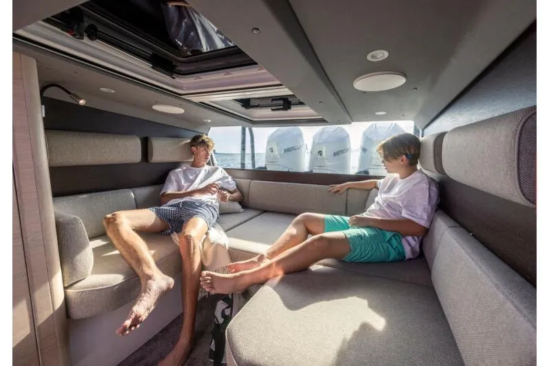 Slide: The Image of Interior of 2027 Axopar 45 Sun-Top boat with two people relaxing on cushioned seating. - 12