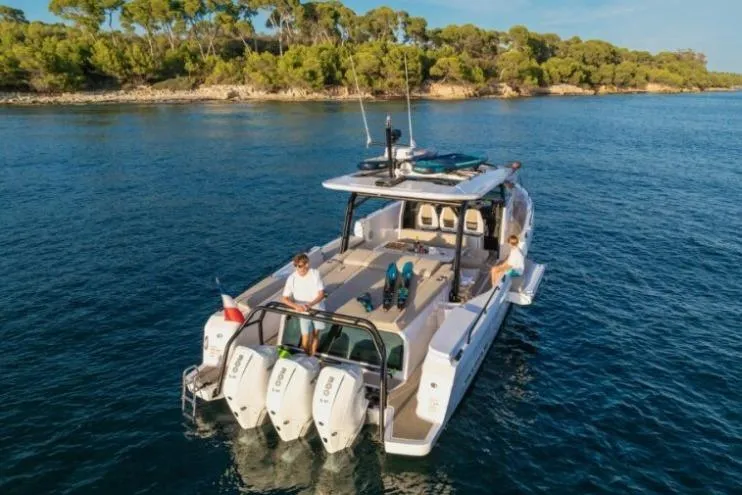 Slide: The Image of 2027 Axopar 45 Sun-Top boat cruising on serene waters near a lush coastline. - 2