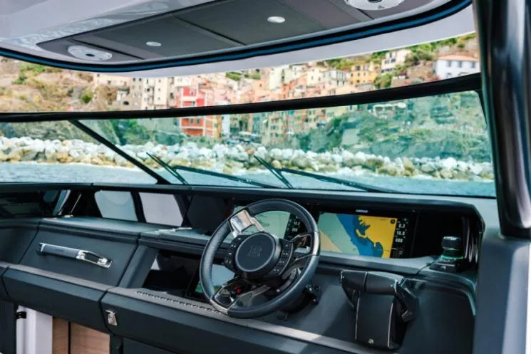 Slide: The Image of Interior view of 2027 Axopar 45 Sun-Top boat with modern dashboard and scenic coastal backdrop. - 3