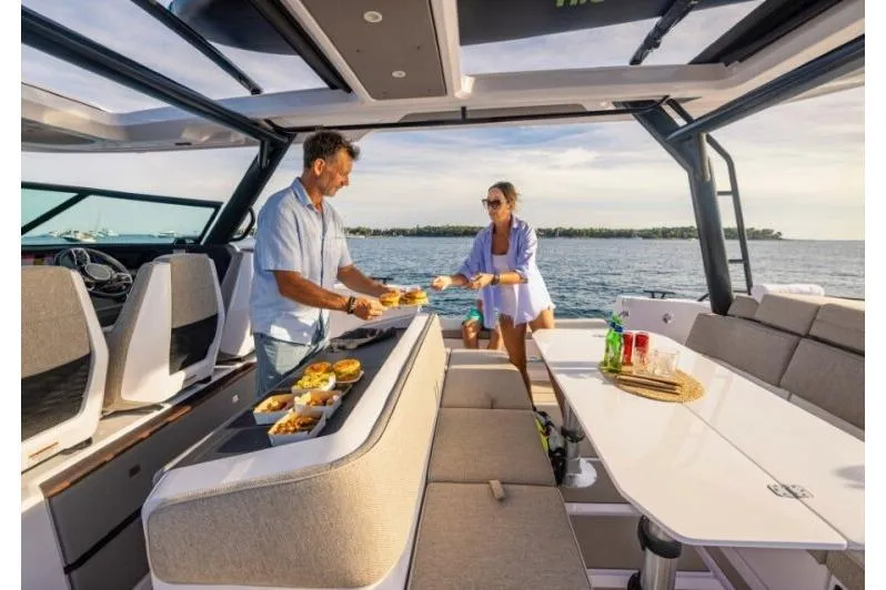 Slide: The Image of Couple enjoying a meal on a 2027 Axopar 45 Sun-Top boat, with scenic ocean view. - 5
