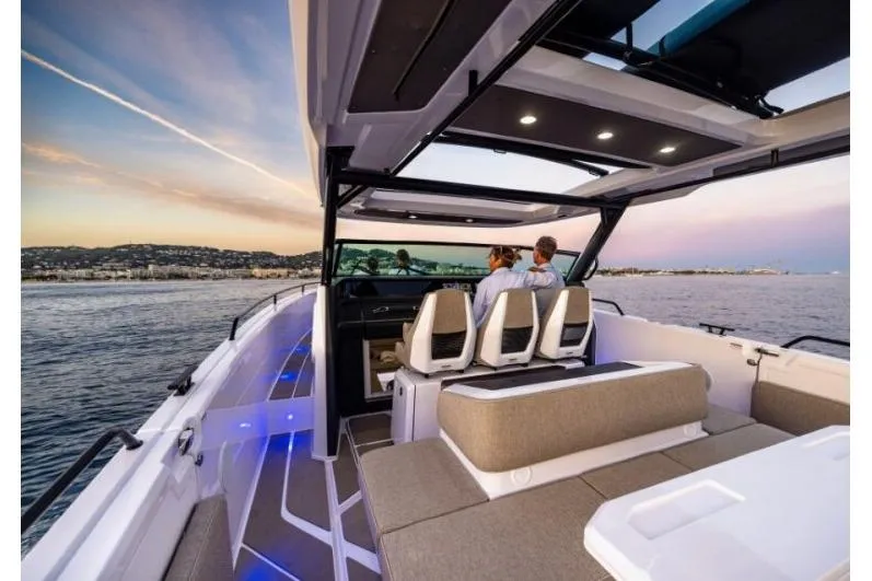 Slide: The Image of 2027 Axopar 45 Sun-Top boat cruising at sunset with passengers enjoying the view. - 8