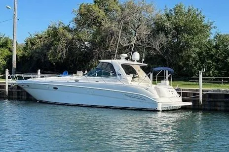 The Image of 2001 Sea Ray 460 Sundancer yacht docked by lush greenery. - 1