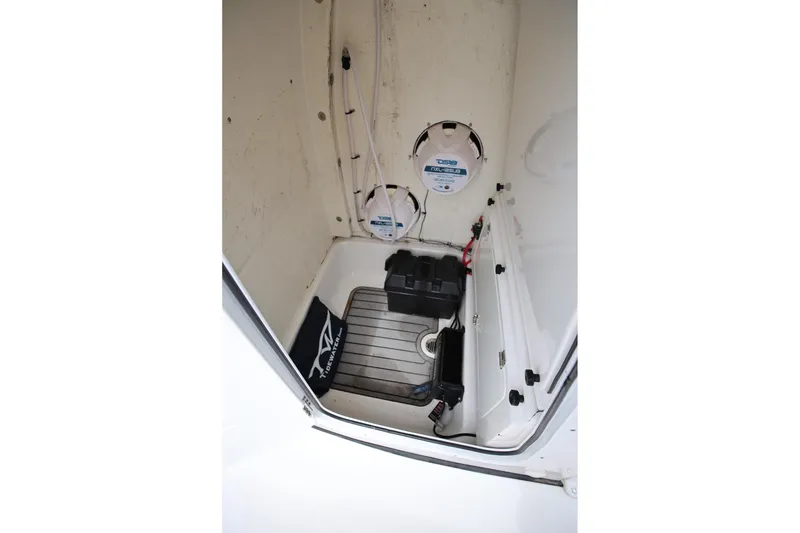 Slide: The Image of 2023 Tidewater 232 SS boat interior storage compartment with speakers and battery. - 16
