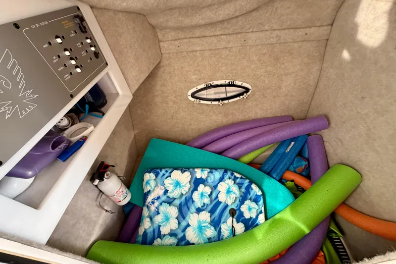 Slide: The Image of Storage compartment in a 2000 Formula 280 Bowrider with pool noodles and floral cushion. - 24