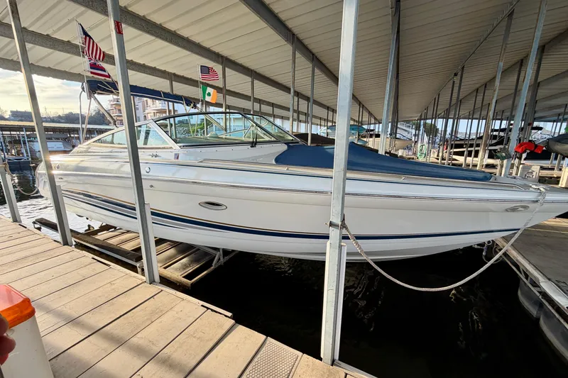 Slide: The Image of 2000 Formula 280 Bowrider docked under a covered marina with flags displayed. - 3