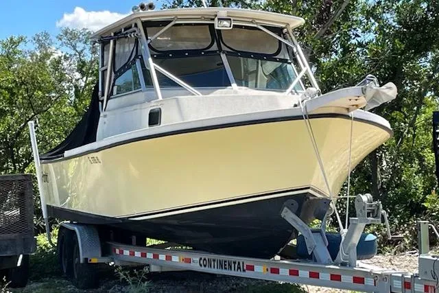 The Image of 2001 Parker 2510 Walkaround boat on trailer, surrounded by trees. - 0