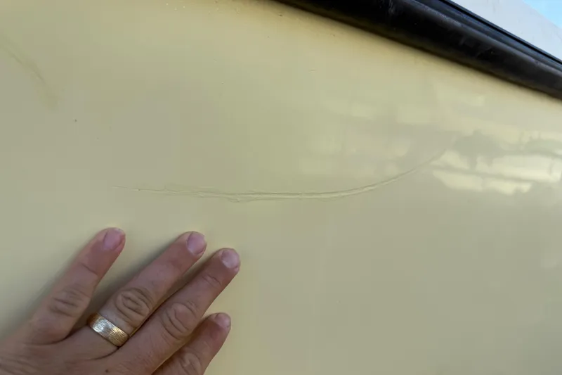 Slide: The Image of Close-up of a hand inspecting a crack on a 2001 Parker 2510 Walkaround boat hull. - 11