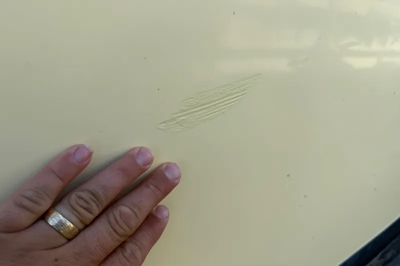 Slide: The Image of Close-up of a 2001 Parker 2510 Walkaround boat with a scratch and hand for scale. - 12