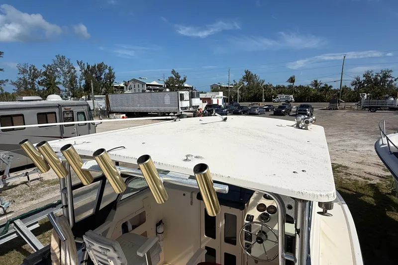 Slide: The Image of 2001 Parker 2510 Walkaround boat with rod holders, parked outdoors under clear skies. - 42