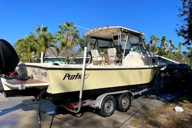 Slide: The Image of 2001 Parker 2510 Walkaround boat on trailer, parked outdoors with palm trees in background. - 1