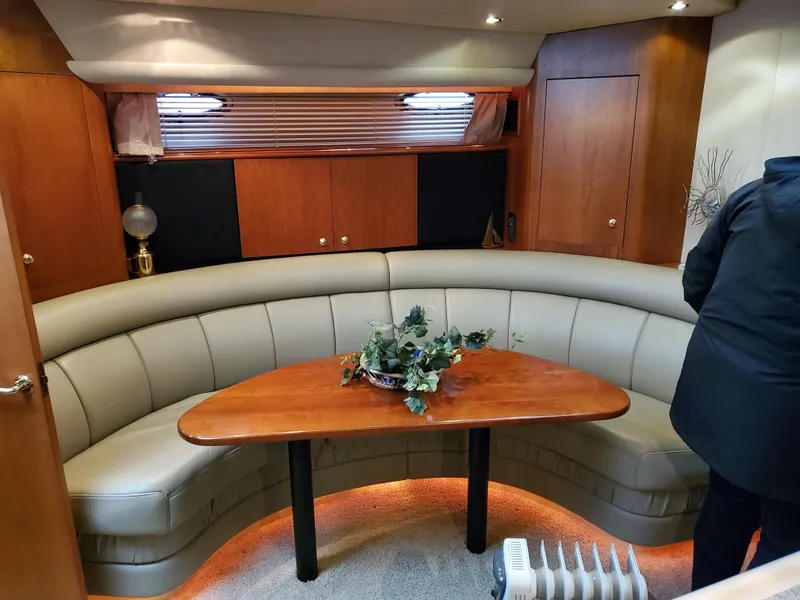 Slide: The Image of Interior of 2002 Cruisers Yachts 4270 Express with curved seating and wooden table. - 4