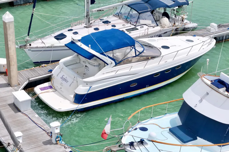 Slide: The Image of 2004 Regal Commodore 3860 yacht docked in marina with blue canopy and sleek design. - 2