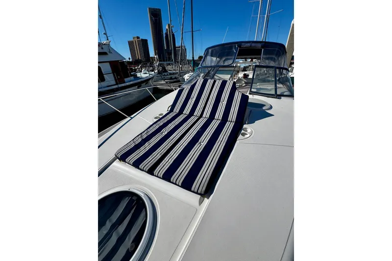 Slide: The Image of 2004 Regal Commodore 3860 yacht with striped sunbed on deck, docked in marina. - 27