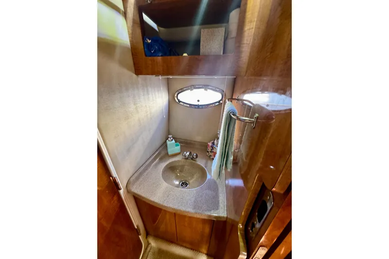 Slide: The Image of 2004 Regal Commodore 3860 yacht bathroom with sink, mirror, and porthole window. - 64