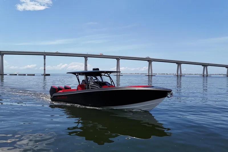 Slide: The Image of 2026 Nor-Tech 340 Sport Center Console boat cruising under a bridge on a sunny day. - 12