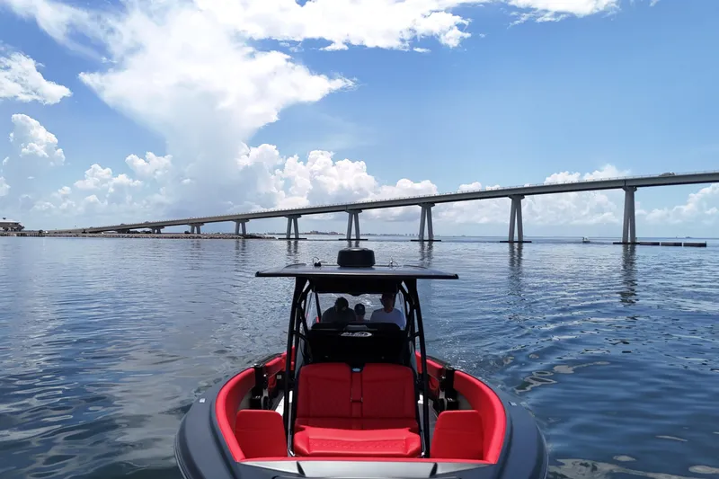 Slide: The Image of 2026 Nor-Tech 340 Sport Center Console boat on calm water near a bridge under a blue sky. - 13