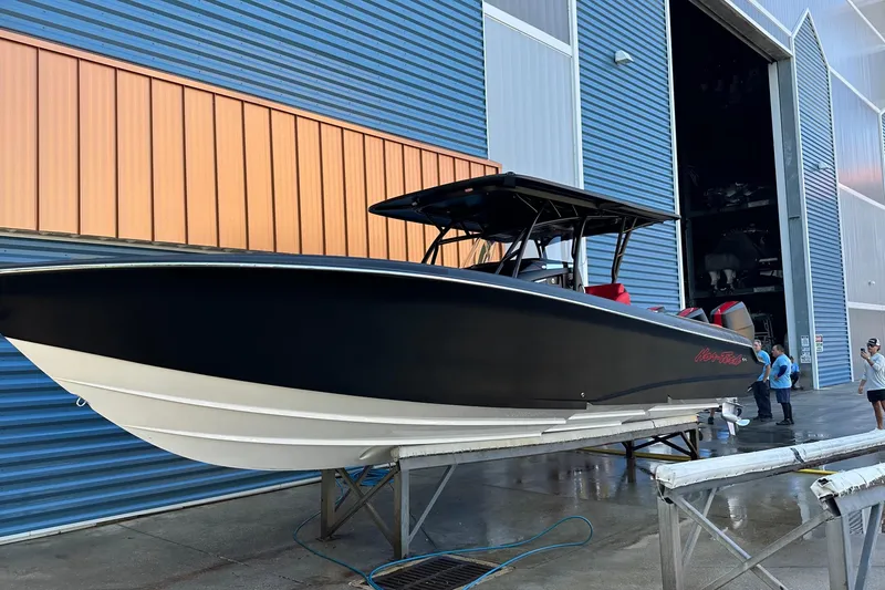 Slide: The Image of 2026 Nor-Tech 340 Sport Center Console boat on display outside a blue warehouse. - 23