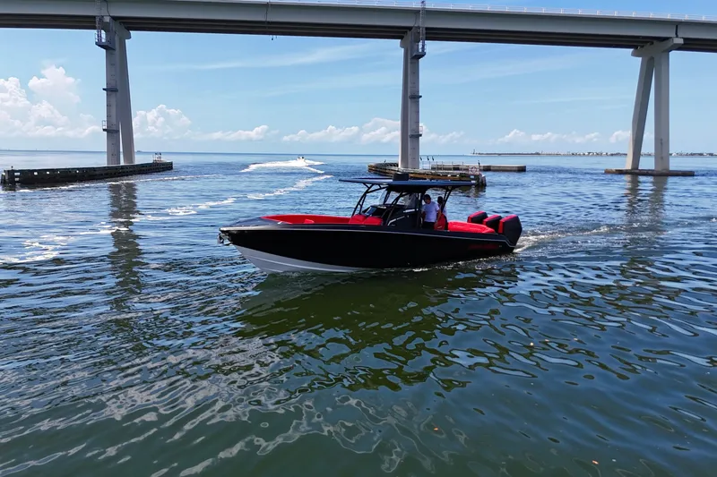 Slide: The Image of 2026 Nor-Tech 340 Sport Center Console boat cruising under a bridge on a sunny day. - 4