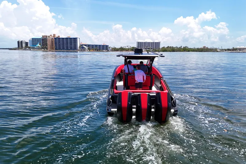 Slide: The Image of 2026 Nor-Tech 340 Sport Center Console cruising on a sunny day near coastal buildings. - 5