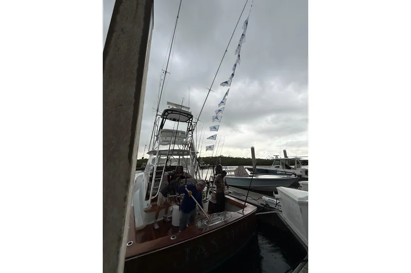 Slide: The Image of 2022 Winter Custom Yachts 38 Walk Around docked, with fishing flags and overcast sky. - 35