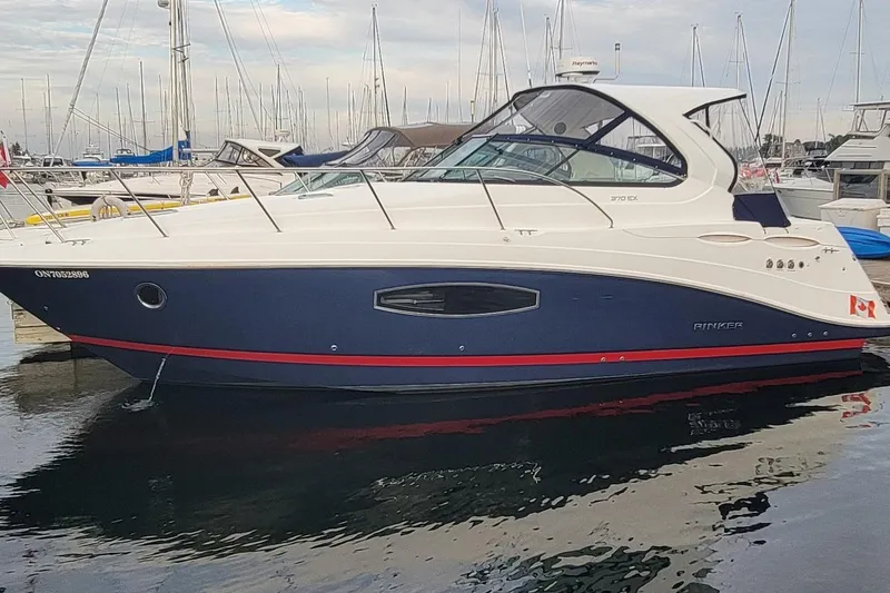 Slide: The Image of 2019 Rinker EX 370 boat docked in marina, sleek design, blue and white exterior. - 0