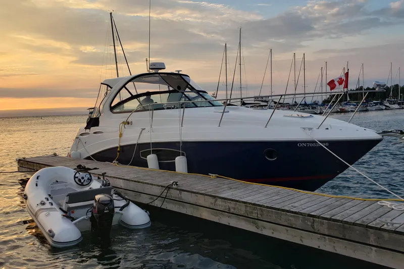 Slide: The Image of 2019 Rinker EX 370 yacht docked at sunset with inflatable boat nearby. - 2