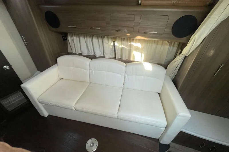 Slide: The Image of White sofa in 2019 Rinker 370 EX cabin with wooden cabinets and curtains. - 24