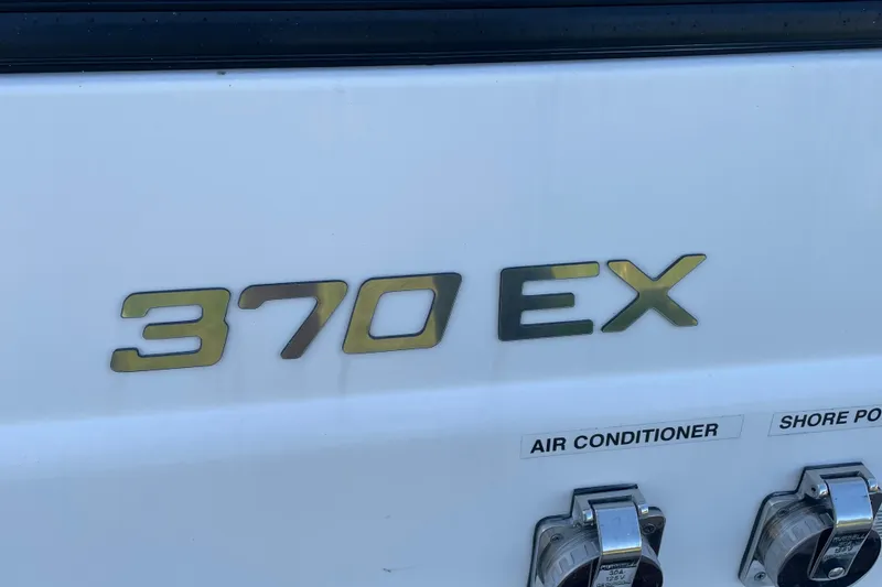 Slide: The Image of 2019 Rinker 370 EX boat model nameplate with air conditioner and shore power outlets. - 6