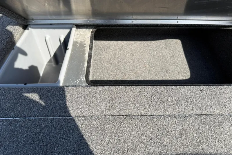 Slide: The Image of 2023 Crestliner 1700 Storm boat storage compartments with gray carpeted interior. - 14