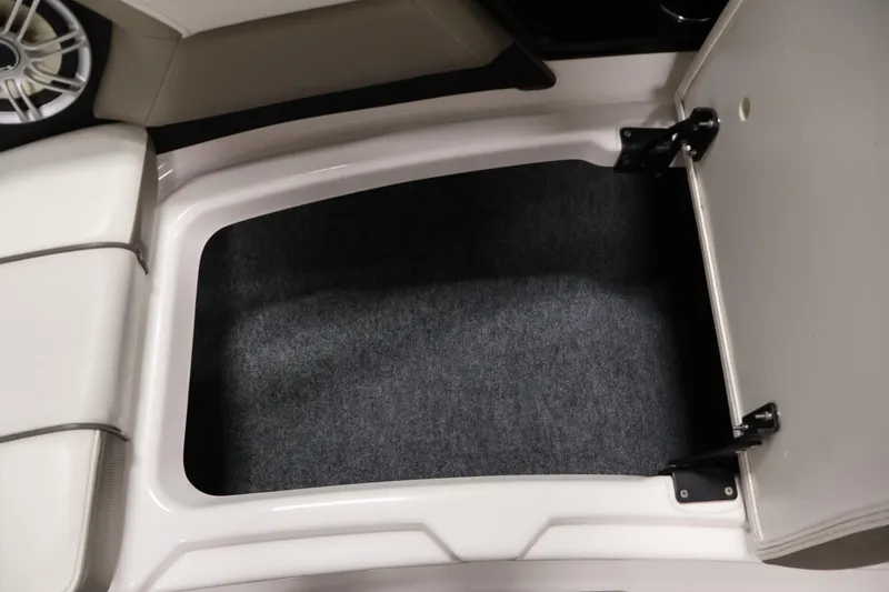 Slide: The Image of 2017 Yamaha Boats 212 Limited S storage compartment with open hatch and carpeted interior. - 16