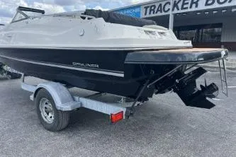 Slide: The Image of 2017 Bayliner 195 Deck Boat on trailer, parked outdoors near a Tracker Boats sign. - 4