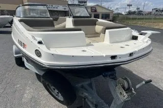 Slide: The Image of 2017 Bayliner 195 Deck Boat on trailer, parked outdoors, showcasing spacious seating and sleek design. - 6